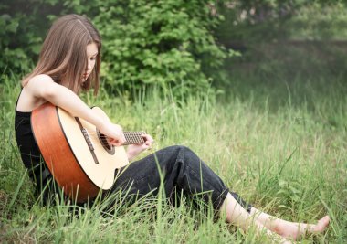 Parkta gitar çalan genç kız.