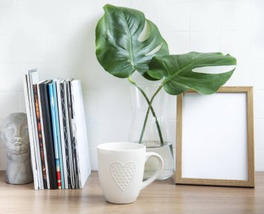 Ofis masasında yığınla not defteri, ofis malzemeleri ve ev bitkileri var.