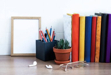 Masaüstünde bir yığın kitap var. Masada çeşitli kitap ve ofis malzemeleri var.