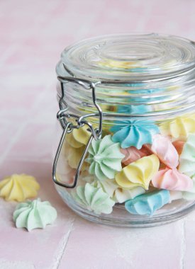 Cam kavanozda pembe fayansların üzerinde küçük renkli kremalar var.