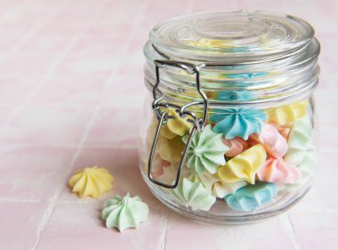 Cam kavanozda pembe fayansların üzerinde küçük renkli kremalar var.