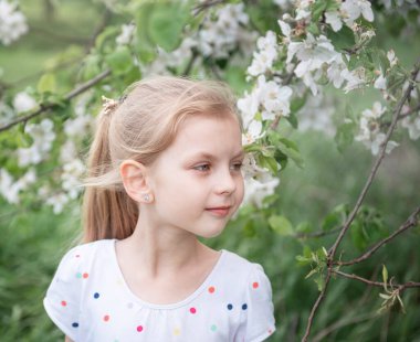 Elma bahçesindeki çiçek açan ağacın arasında küçük sevimli bir kız.