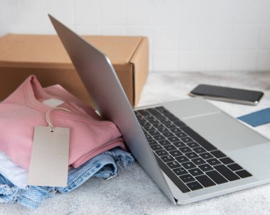 İnternetten alışveriş konsepti. Bir dizüstü bilgisayar ve karton bir kutuda kadın kıyafetleri. Elbise teslimatı..