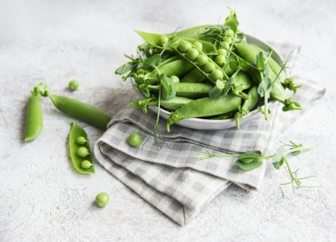 Taze bezelye kabukları ve çimentoda filizlenen yeşil bezelyeler. Sağlıklı beslenme kavramı, taze sebzeler