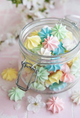 Cam kavanozda pembe fayansların üzerinde küçük renkli kremalar var.