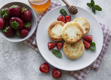 Süzme peynirli krep, seramik tabakta taze çilekli ricotta böreği. Sağlıklı ve lezzetli bir sabah kahvaltısı. Gri beton arkaplan.