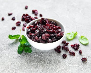 Beyaz kase, gri beton arka planda kurutulmuş kirazlarla dolu.