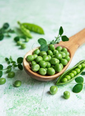 Taze yeşil bezelye kabukları ve yeşil ahşap arka planda lahanaları olan yeşil bezelyeler. Sağlıklı beslenme kavramı, taze sebzeler