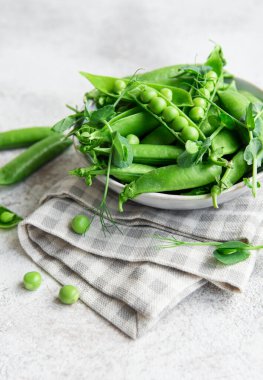 Taze bezelye kabukları ve çimentoda filizlenen yeşil bezelyeler. Sağlıklı beslenme kavramı, taze sebzeler