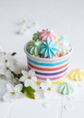 Kâğıt kasenin arka planında küçük renkli kremalar var.