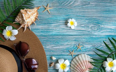 Yaz tatili kavramı. Hasır şapka ve deniz kabuklu plaj aksesuarları ve mavi ahşap arka planda deniz yıldızı.