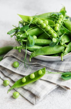 Taze bezelye kabukları ve çimentoda filizlenen yeşil bezelyeler. Sağlıklı beslenme kavramı, taze sebzeler