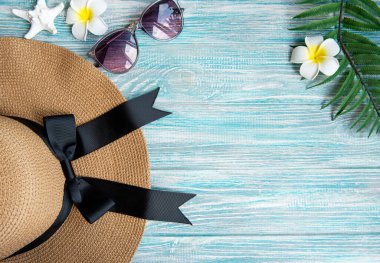 Yaz tatili kavramı. Hasır şapka ve mavi ahşap arka planda frangipani çiçekleri