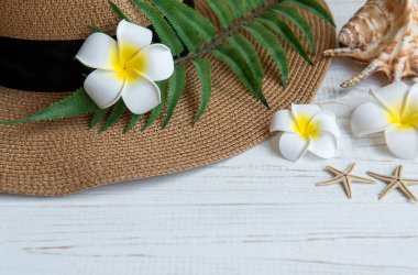 Yaz tatili kavramı. Hasır şapka ve deniz kabuklu plaj aksesuarları ve beyaz ahşap arka planda deniz yıldızı.