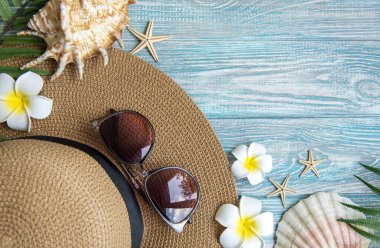 Yaz tatili kavramı. Hasır şapka ve deniz kabuklu plaj aksesuarları ve mavi ahşap arka planda deniz yıldızı.
