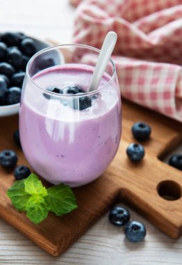 Eski ahşap arka planda yabanmersinli bir bardak yaban mersini yoğurdu..