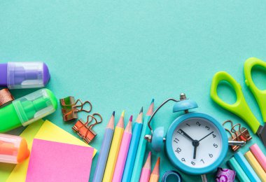 Yeşil arkaplandaki farklı kırtasiye malzemelerinin çerçevesi, metin için boş alanı olan düz bir yer. Okula geri dön.