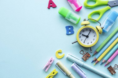 Mavi arkaplanda farklı kırtasiye malzemesi çerçevesi, metin için boş alanı olan düz bir yer. Okula geri dön.