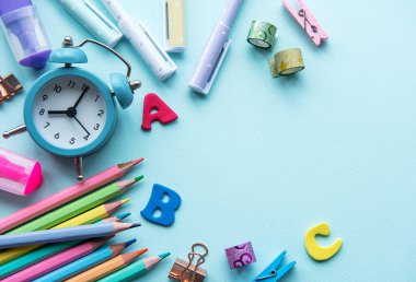 Mavi arkaplanda farklı kırtasiye malzemesi çerçevesi, metin için boş alanı olan düz bir yer. Okula geri dön.