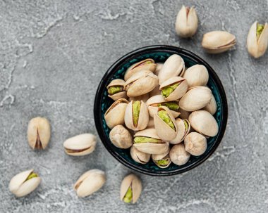 Gri beton arka planda fıstıklı kase