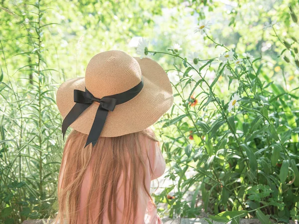 花に囲まれた藁帽子の少女 長い髪をした幸せな少女ブロンドの肖像画 バックビュー — ストック写真