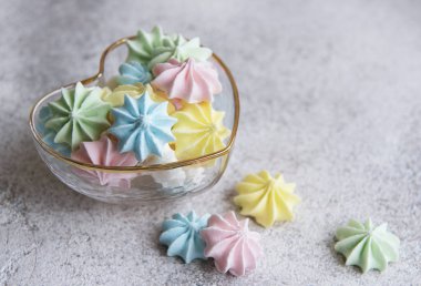 Kalp şeklindeki kasede beton arka planda küçük renkli kremalar.