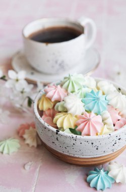 Kahveli bir fincan ve fayanslı arka planda küçük kremalar.