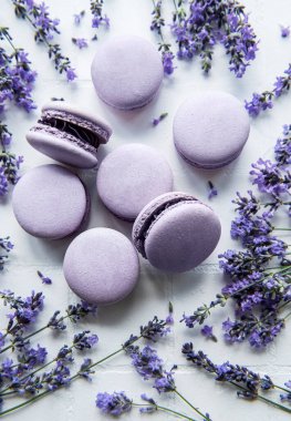 Beyaz fayanslı lavanta aromalı Fransız Makaronları ve taze lavanta çiçekleri.