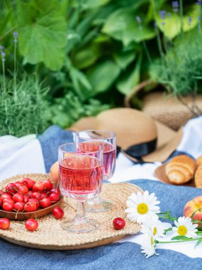 Lavanta tarlalarında piknik. Bardakta gül şarabı, battaniyede kiraz ve hasır şapka