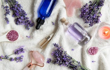 Lavanta kaplıcası. Gerekli yağlar, deniz tuzu, havlular ve yüz silindiri. Lavanta çiçekli doğal bitki kozmetiği.