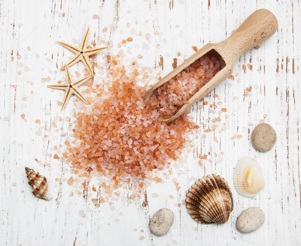sea salt in wooden spoon with sea shells and starfish