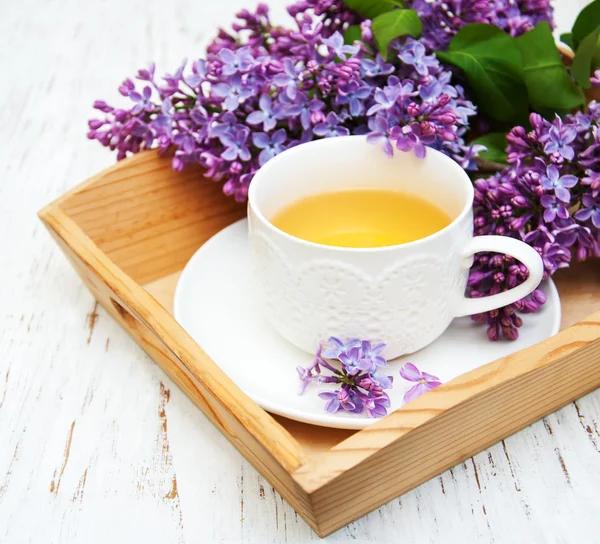 Cup of tea and lilac flowers — Stock Photo, Image