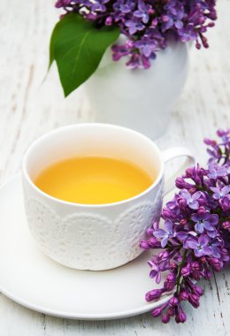 Fincan çay ve eflatun çiçekler