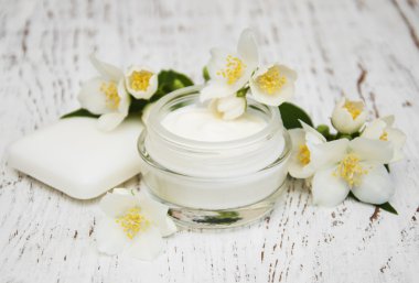 face and body cream moisturizers with jasmine flowers on white w clipart