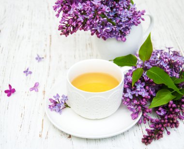 Fincan çay ve eflatun çiçekler