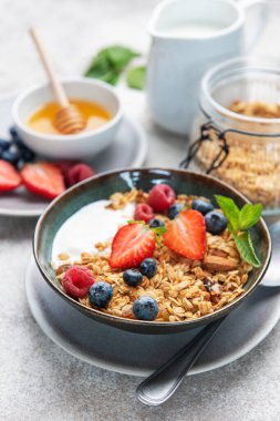 Granola and yogurt bowl topping with fresh strawberries, blueberries, and raspberries