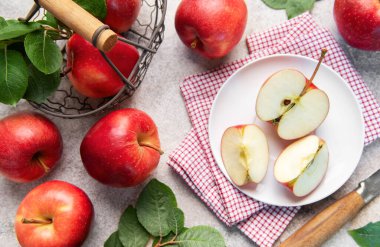 Kırmızı elmalar, bütün ve dilimlenmiş, yeşil yapraklı ve hasat sepetli