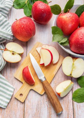 Tahta kesme tahtasındaki taze kırmızı elmalar sağlıklı meyve atıştırmalıkları hazırlıyor.