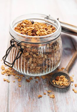 Yulaflı ev yapımı granola ve ahşap masada cam bir kavanozda kurutulmuş meyve.