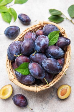 Hasır bir sepeti yapraklarla dolduran erikler olgun meyve ve dilimleri gösteriyor.