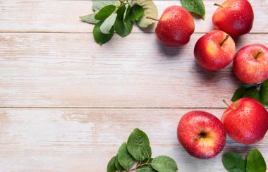 Yeşil yapraklı taze kırmızı gala elmaları ve kırsal ahşap yüzeye su damlaları.