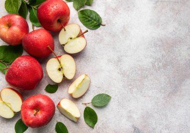 Olgun kırmızı elmalar ve elma dilimleriyle su damlaları, dokulu yüzeyin üst görüntüsü