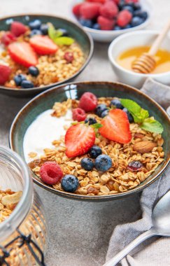 Sağlıklı bir kahvaltı için taze çilek, yabanmersini, ahududu, yoğurt, fındık ve bal dolu granola kaseleri.