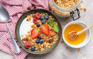 Bir kase granola ve taze meyve ve bademle kaplı yoğurt.