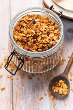 Yulaflı ev yapımı granola ve ahşap masada cam bir kavanozda kurutulmuş meyve.