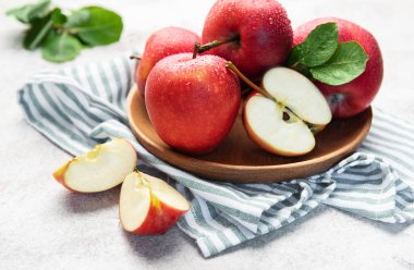 Su damlaları ve tahta tabakta dilimler ve çizgili havluyla kıtır kıtır kırmızı elmalar.