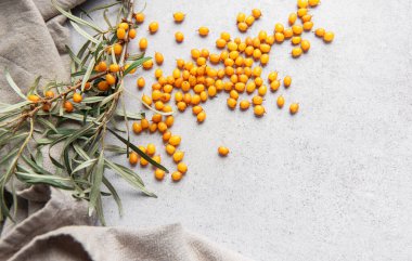 Olgun portakallı deniz dikenli üzümleri keten bir kumaşın üzerine serpiştirilmiş bir dalla