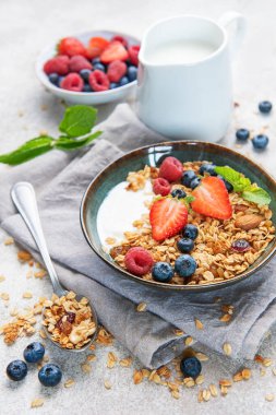 Sağlıklı bir kahvaltı için taze çilek, yabanmersini, ahududu, yoğurt, fındık ve bal dolu granola kaseleri.