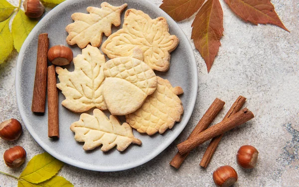Homemade autumn shaped cookies with cinnamon sticks and hazelnuts, representing fall season baking