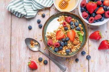 Granola, yogurt, strawberries, blueberries, and raspberries creating a nutritious breakfast